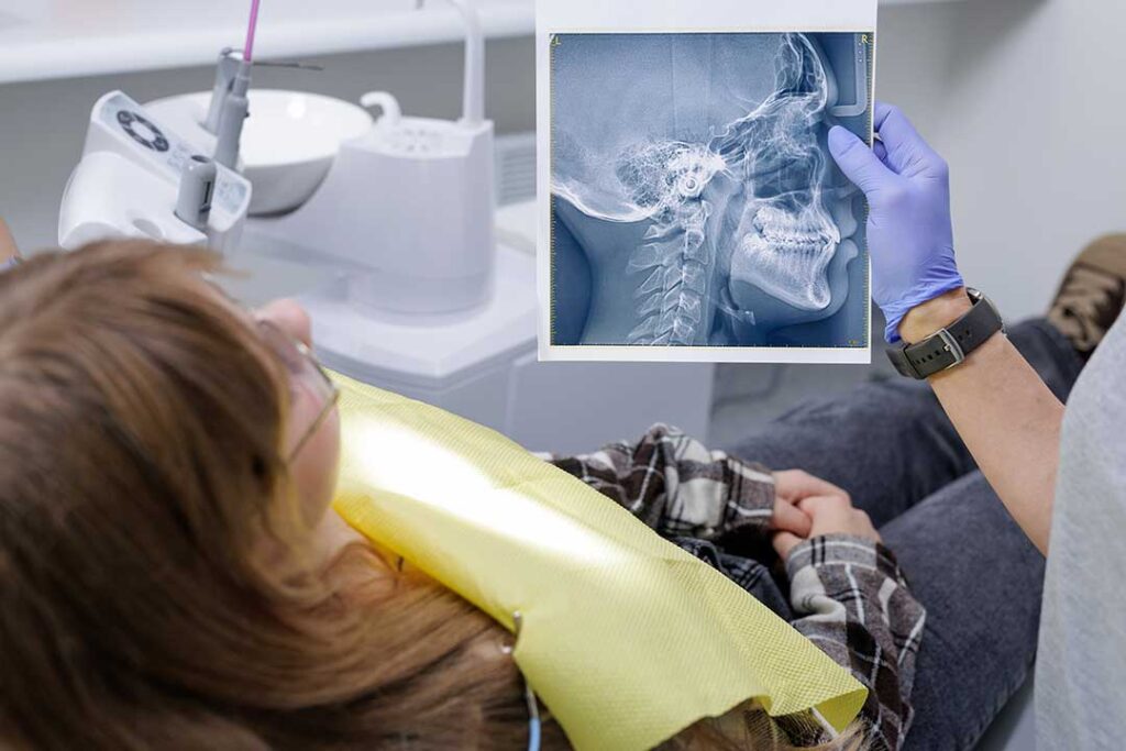 Parent gently brushes a toddler’s teeth with a small soft toothbrush at a bathroom sink.