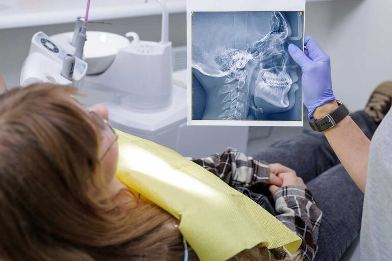 Parent gently brushes a toddler’s teeth with a small soft toothbrush at a bathroom sink.