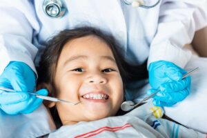 Caregiver holds a baby during a gentle first dental examination in a bright pediatric dental room.